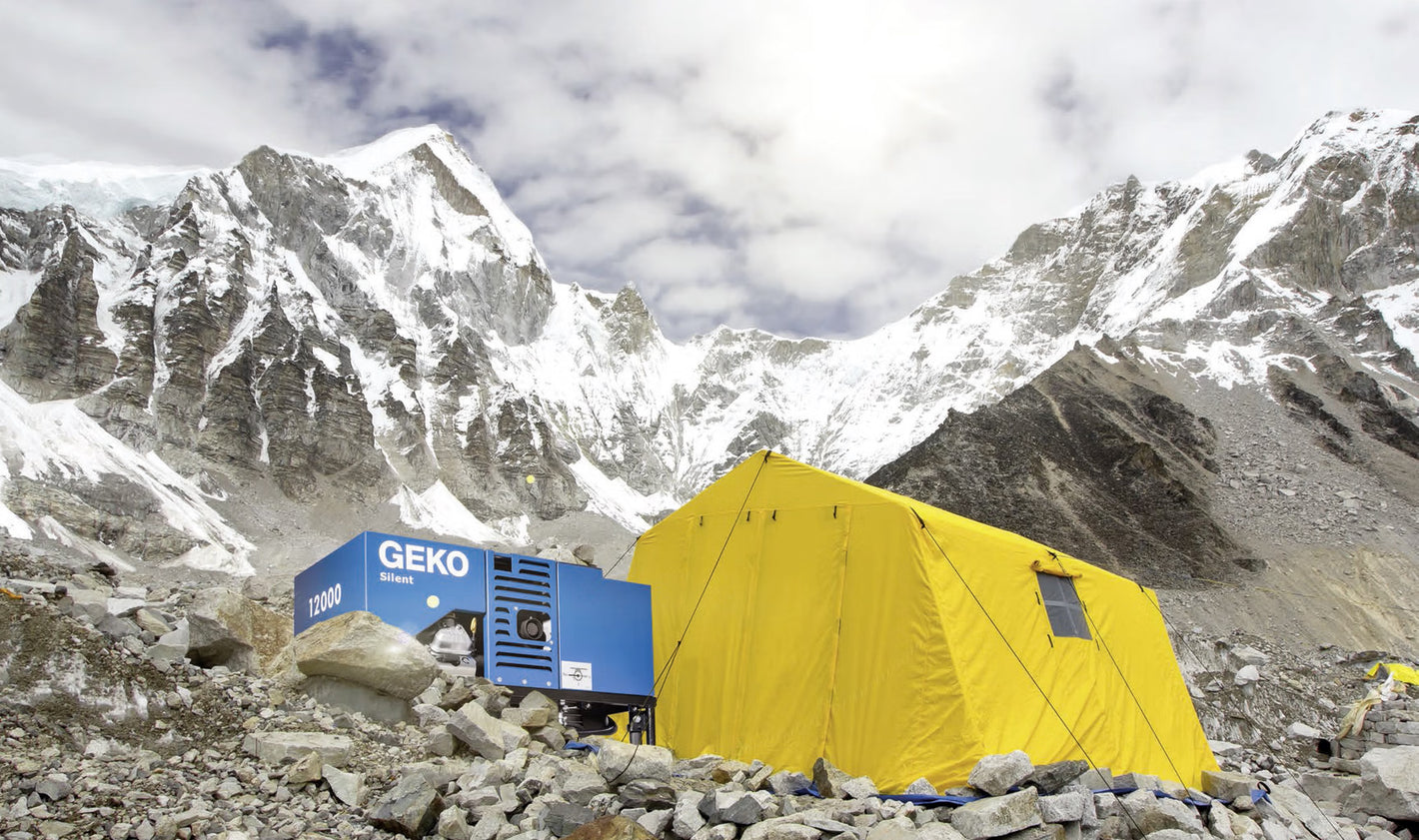 Yellow tent and blue GEKO generator in a mountainous area with snow-capped peaks.